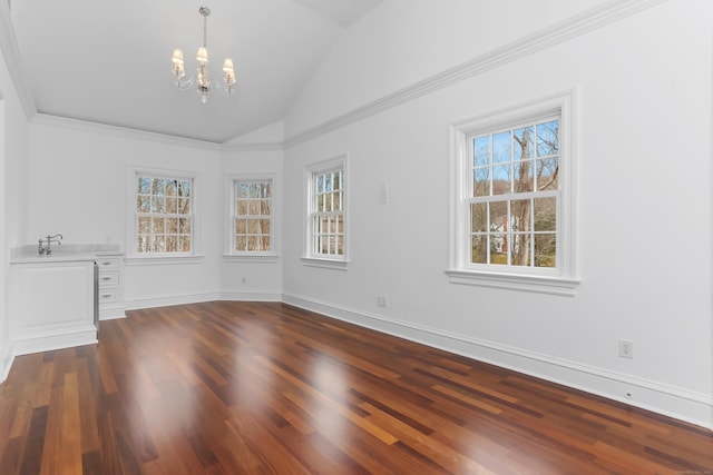 empty room with dark wood-type flooring, an inviting chandelier, a healthy amount of sunlight, and vaulted ceiling