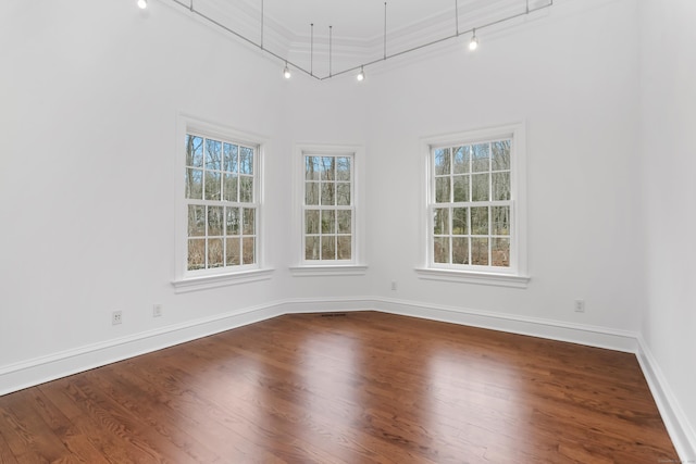 unfurnished room featuring crown molding, plenty of natural light, baseboards, and dark wood-style flooring