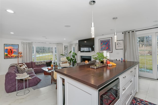 kitchen featuring dark countertops, open floor plan, beverage cooler, and white cabinetry