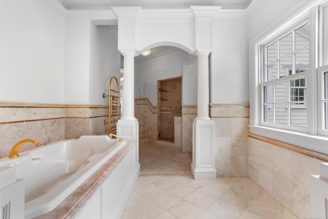 full bath with a wainscoted wall, ornamental molding, tile walls, a bath, and ornate columns