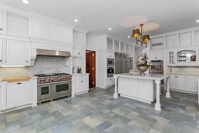 kitchen with under cabinet range hood, white cabinetry, a breakfast bar area, light countertops, and built in appliances