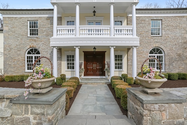 property entrance featuring a balcony and stone siding