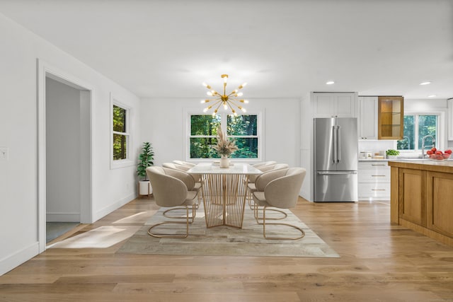 dining space featuring a healthy amount of sunlight, light wood finished floors, a notable chandelier, and recessed lighting