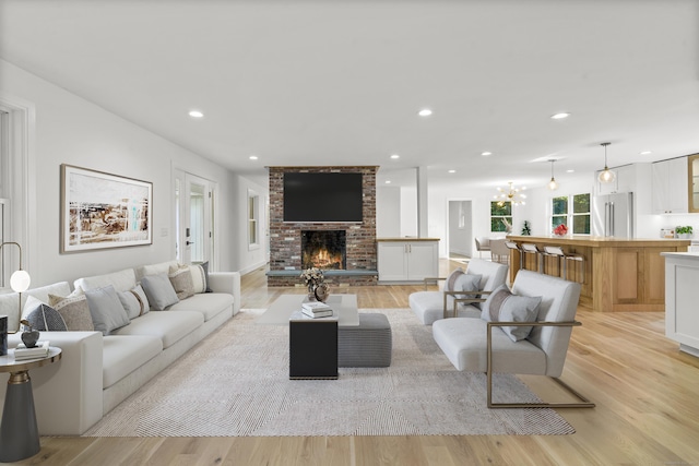 living area with light wood-style floors, recessed lighting, and a brick fireplace