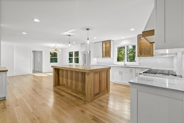 kitchen featuring a sink, appliances with stainless steel finishes, light wood-style floors, and decorative backsplash