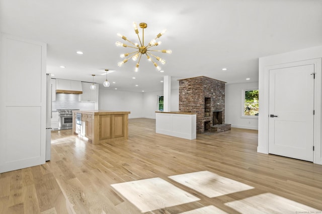 unfurnished living room with recessed lighting, a brick fireplace, and light wood-style floors