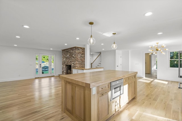 kitchen with a center island, recessed lighting, a brick fireplace, open floor plan, and light wood-type flooring