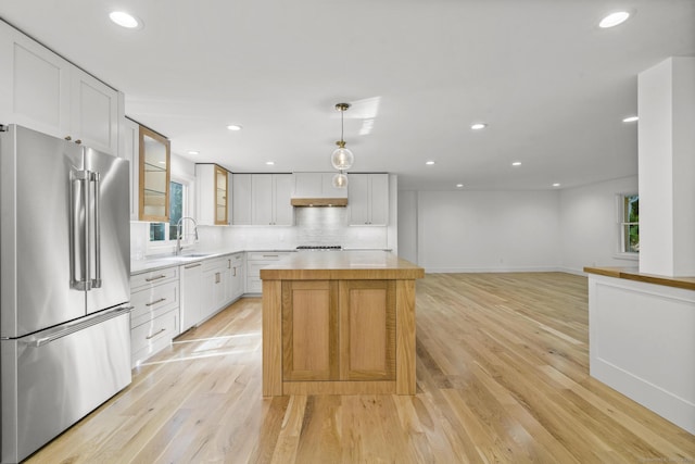 kitchen with paneled dishwasher, high quality fridge, a center island, light wood-type flooring, and a sink