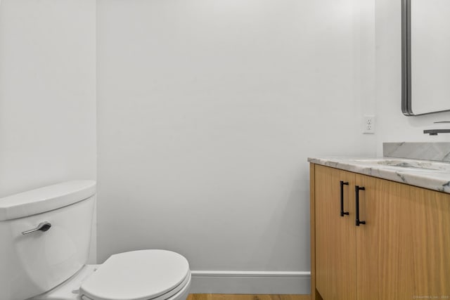 bathroom featuring baseboards, vanity, toilet, and wood finished floors