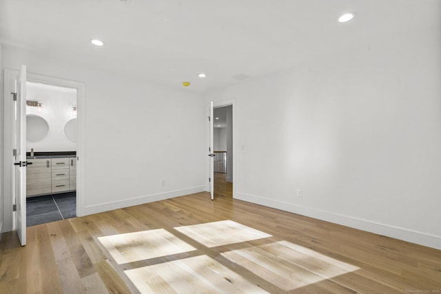 unfurnished bedroom featuring baseboards, connected bathroom, light wood-style flooring, and recessed lighting