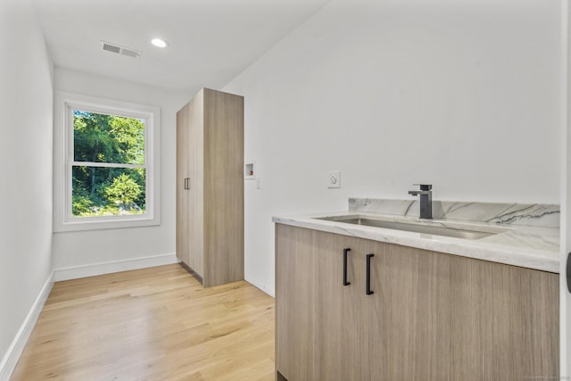 kitchen featuring light wood finished floors, recessed lighting, a sink, modern cabinets, and baseboards