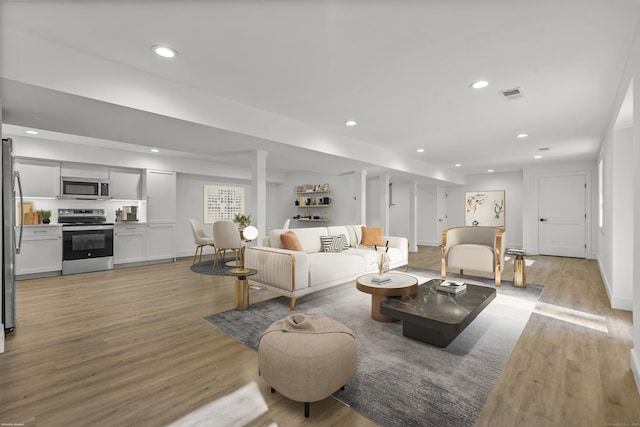 living room with light wood-style floors, recessed lighting, and visible vents