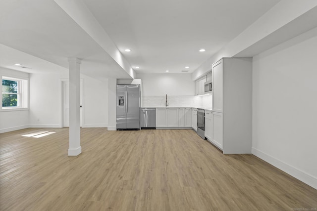 kitchen featuring open floor plan, stainless steel appliances, light wood-type flooring, and decorative backsplash