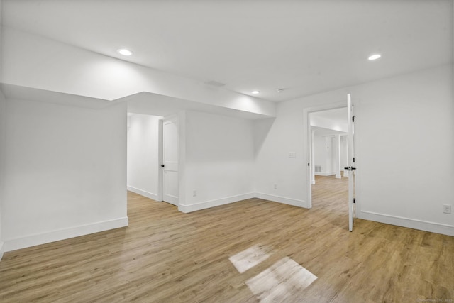 finished below grade area with baseboards, light wood-type flooring, and recessed lighting