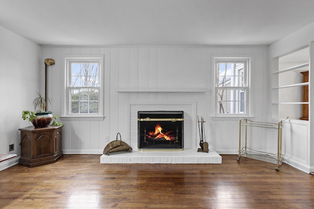 living area with hardwood / wood-style floors, a fireplace, and built in shelves