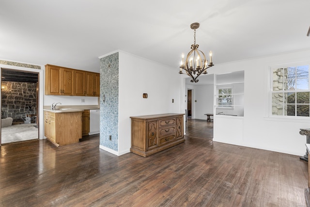 kitchen with decorative light fixtures, light countertops, dark wood-type flooring, white dishwasher, and a sink