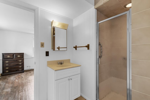 bathroom with wood finished floors, a shower stall, and vanity