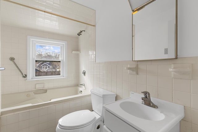 bathroom featuring toilet, tiled shower / bath combo, vanity, and tile walls