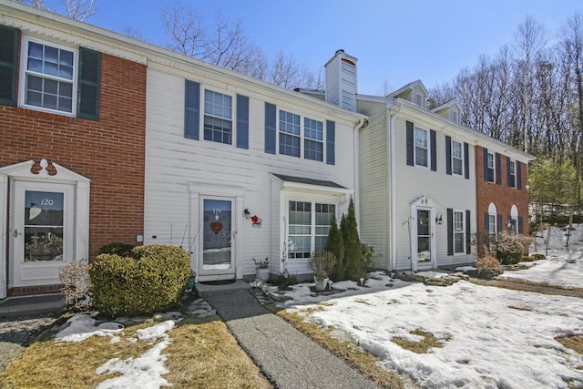 view of front of property with a chimney and brick siding