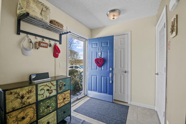 foyer featuring a textured ceiling, baseboards, and light tile patterned floors