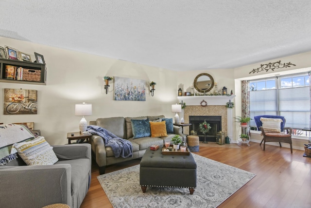 living area with a textured ceiling, a tiled fireplace, and light wood-style floors