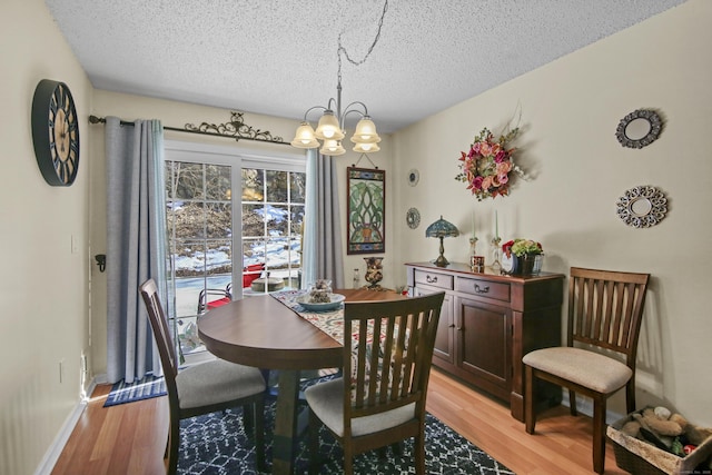 dining room with light wood-type flooring, baseboards, a chandelier, and a textured ceiling