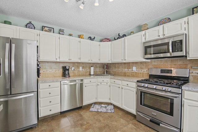 kitchen featuring appliances with stainless steel finishes, a sink, white cabinets, and tasteful backsplash