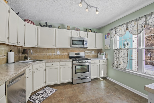 kitchen with appliances with stainless steel finishes, a sink, white cabinets, and decorative backsplash