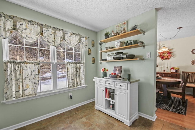 interior space with a textured ceiling, tile patterned flooring, and baseboards