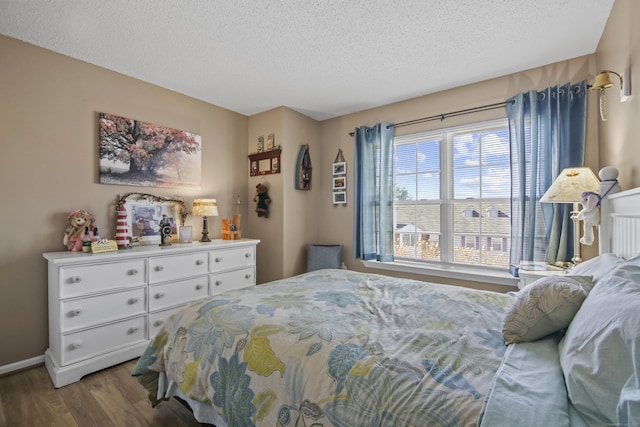 bedroom featuring a textured ceiling, baseboards, and wood finished floors