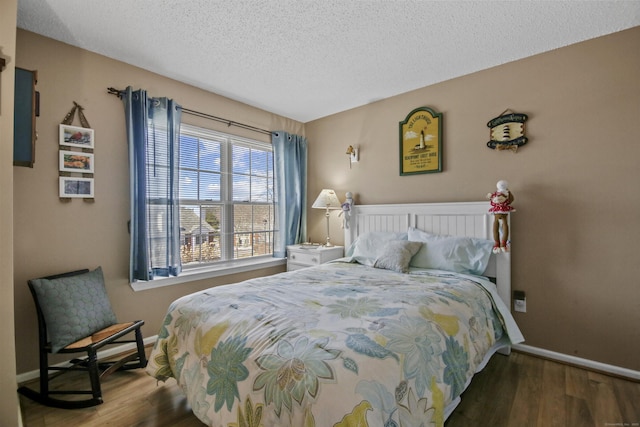 bedroom with a textured ceiling, wood finished floors, and baseboards