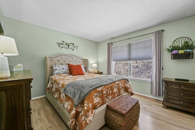 bedroom featuring a textured ceiling, wood finished floors, and baseboards