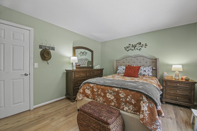 bedroom featuring a textured ceiling, baseboards, and wood finished floors