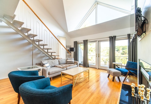 living room featuring stairway, french doors, high vaulted ceiling, and light wood-style floors