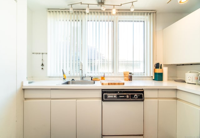 kitchen featuring a sink, white cabinets, white dishwasher, and light countertops