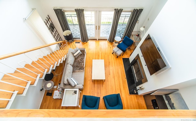 unfurnished living room with stairs, wood finished floors, and french doors