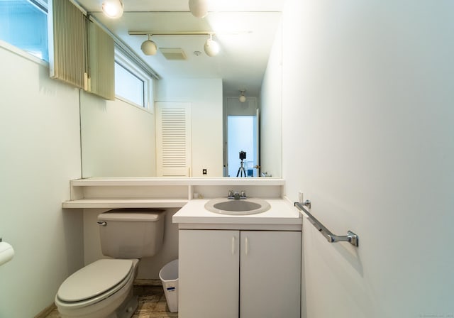 bathroom with rail lighting, toilet, and vanity