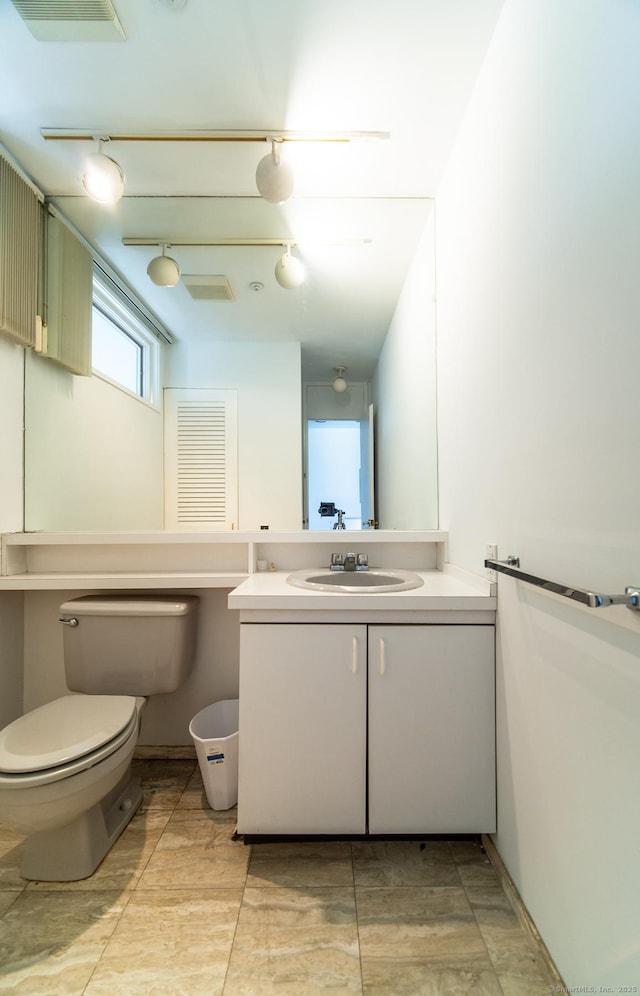 bathroom featuring vanity, toilet, visible vents, and rail lighting