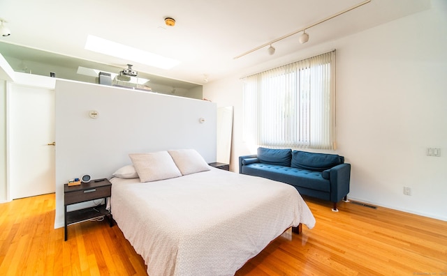 bedroom featuring a skylight, visible vents, wood finished floors, and track lighting