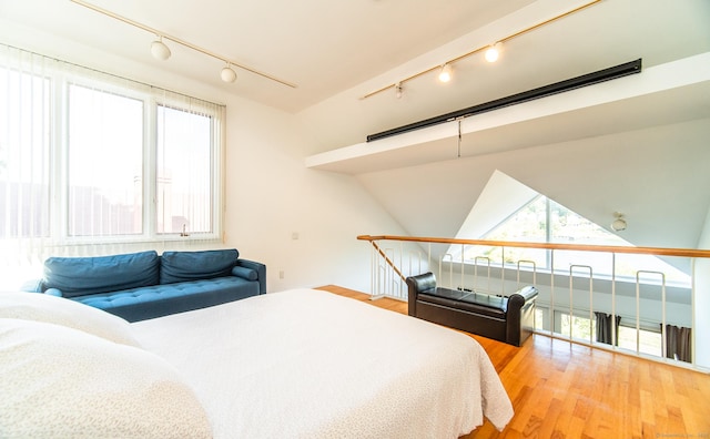 bedroom with track lighting and wood finished floors