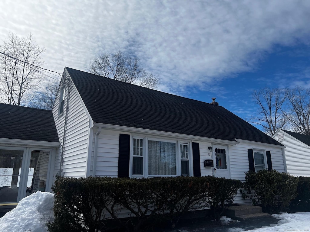 cape cod house featuring roof with shingles