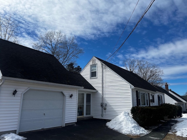 view of home's exterior featuring a garage and a shingled roof