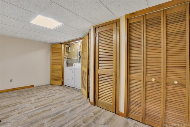 clothes washing area with light wood finished floors, laundry area, washer and dryer, and baseboards