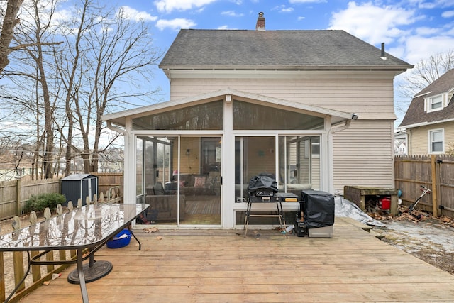 wooden terrace with an outbuilding, a storage unit, a fenced backyard, and a sunroom