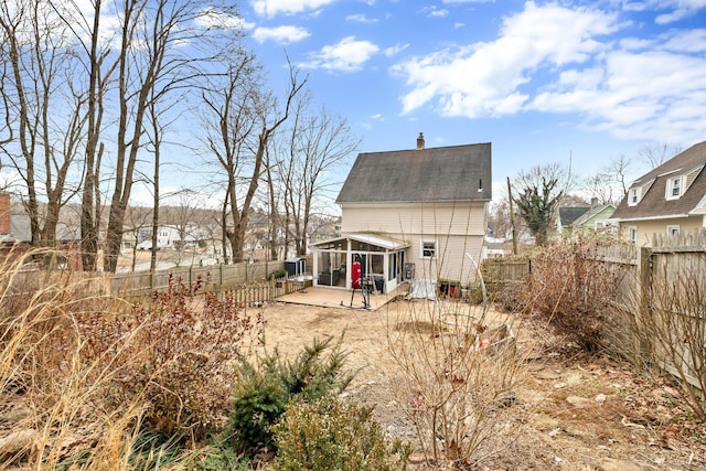 back of house featuring a chimney, a sunroom, a patio area, and a fenced backyard