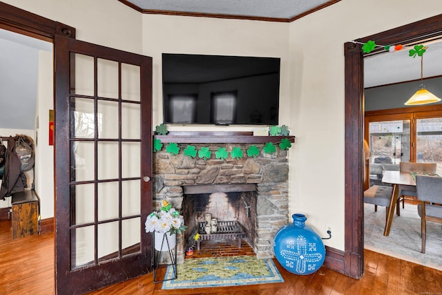 living area featuring baseboards, a fireplace, ornamental molding, and hardwood / wood-style floors