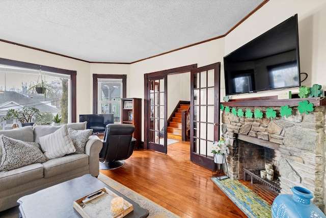 living room with hardwood / wood-style flooring, a fireplace, a textured ceiling, and french doors