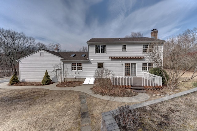 back of house with a chimney and a wooden deck