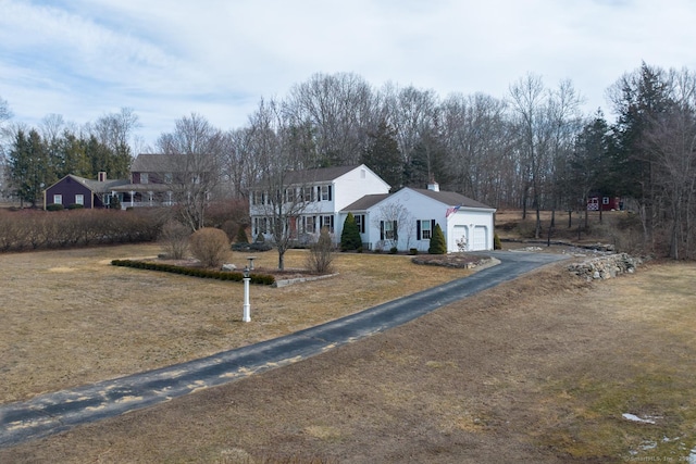 view of front of property with a garage, a chimney, aphalt driveway, and a front yard