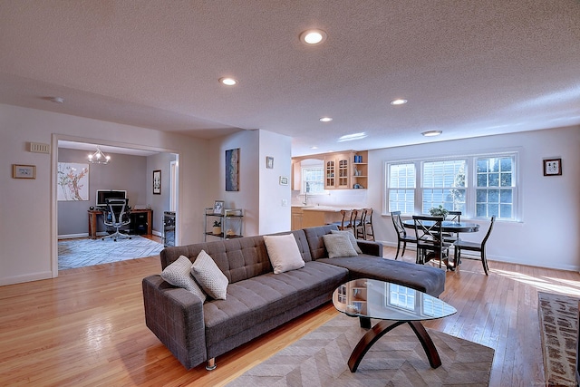 living area featuring recessed lighting, baseboards, a textured ceiling, and light wood finished floors